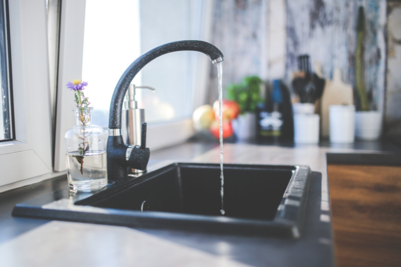 Image of a running tap in a kitchen | Water Hygiene in Commercial properties
